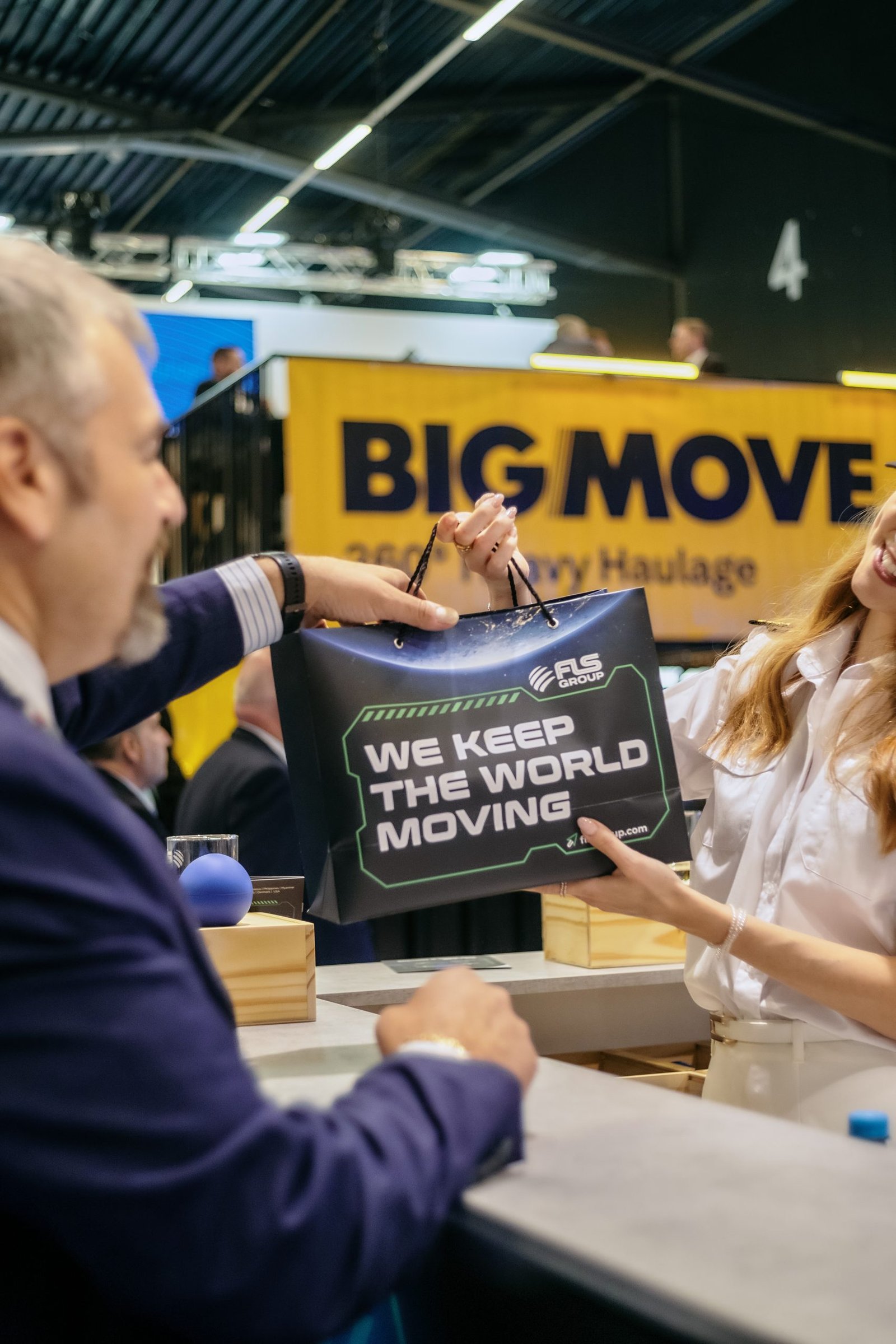 An FLS Group branded gift bag being presented to a guest