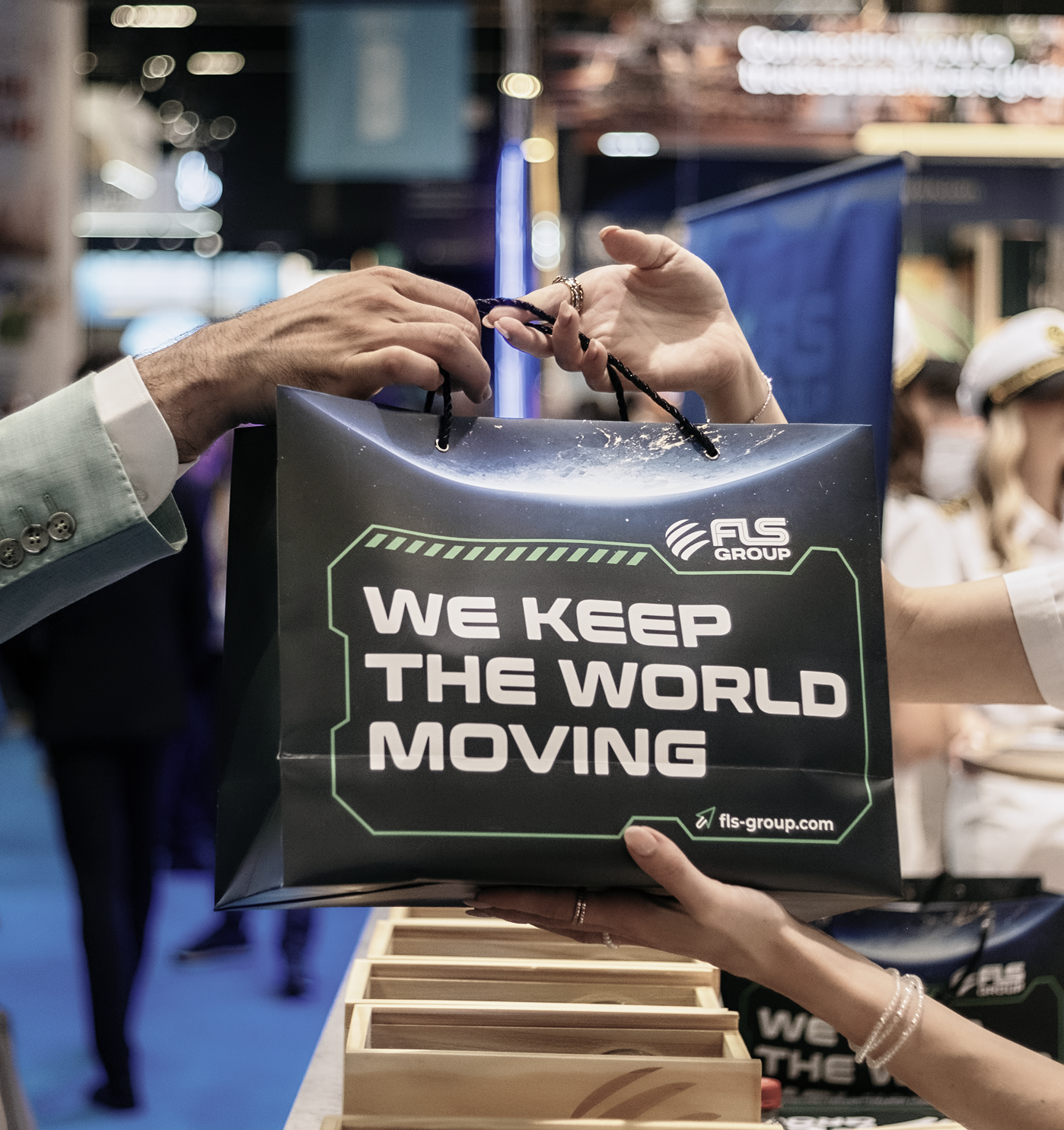 FLS Group branded gift bag handed to an event visitor